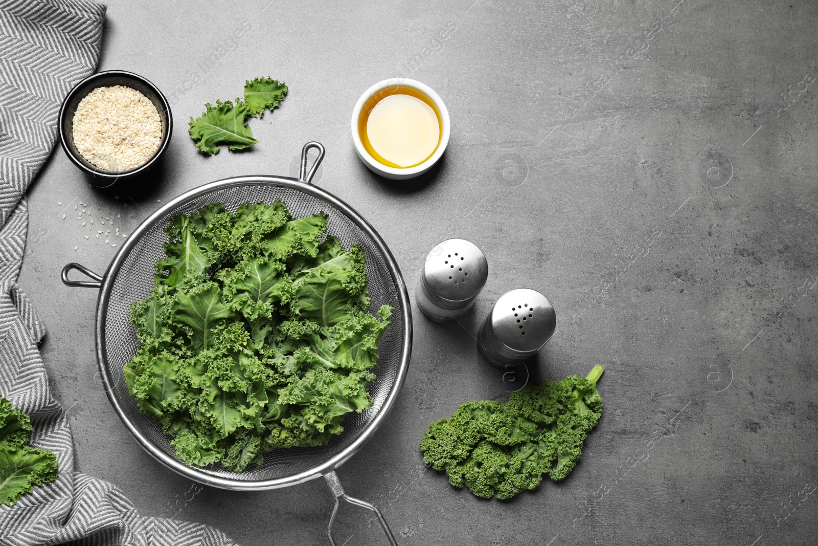 Photo of Raw cabbage leaves on grey table, flat lay. Preparing kale chips