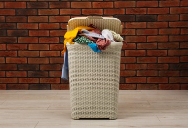 Photo of Plastic laundry basket with clothes near brick wall