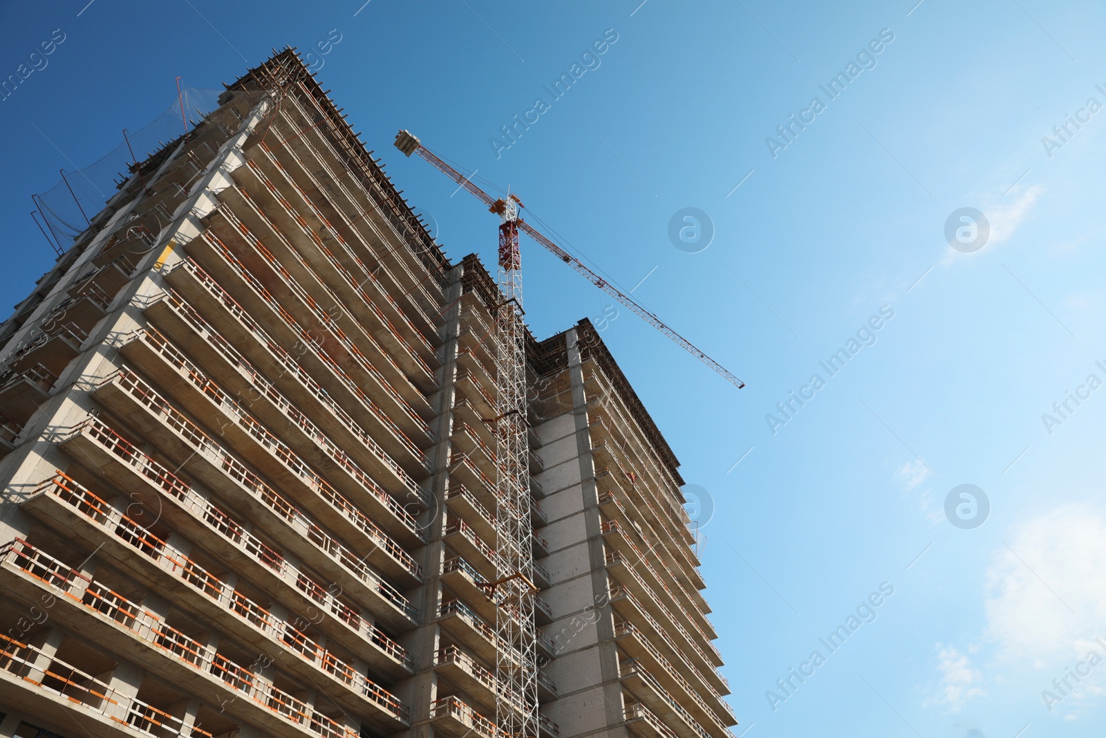 Photo of Construction site with tower crane near unfinished building, low angle view