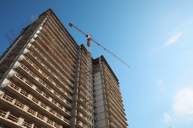 Construction site with tower crane near unfinished building, low angle view