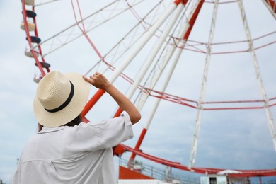 Photo of Young woman near Ferris wheel outdoors, back view