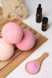 Beautiful aromatic bath bombs and sea salt on white wooden table, closeup