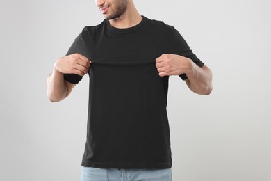 Man wearing black t-shirt on gray background, closeup