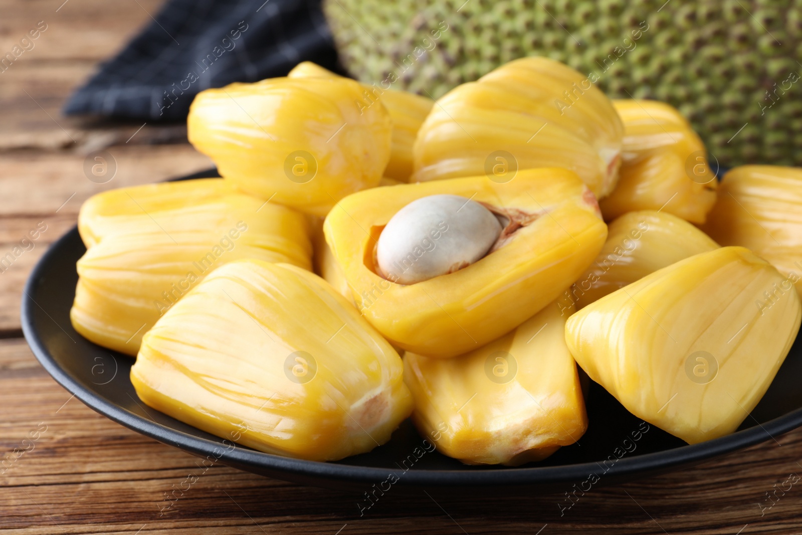 Photo of Fresh exotic jackfruit bulbs on wooden table, closeup
