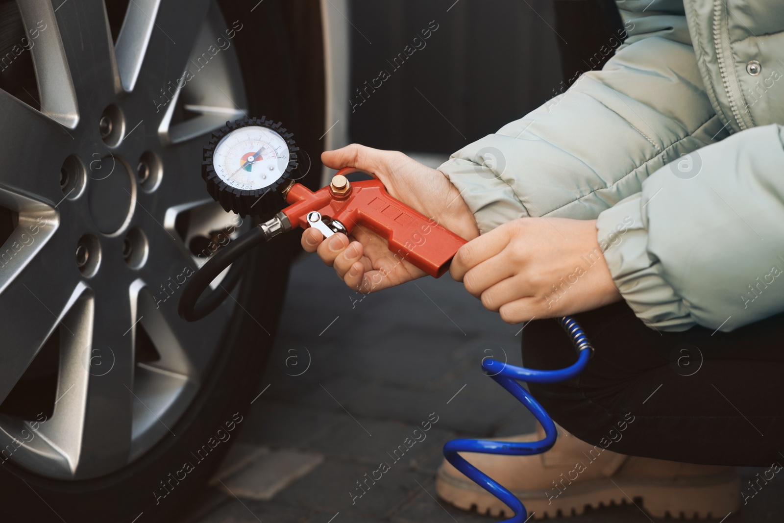 Photo of Young woman inflating tire at car service, closeup