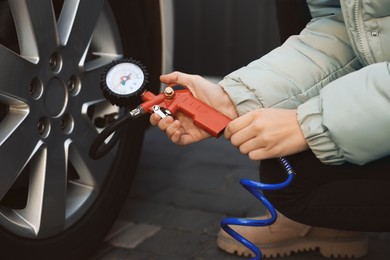 Photo of Young woman inflating tire at car service, closeup