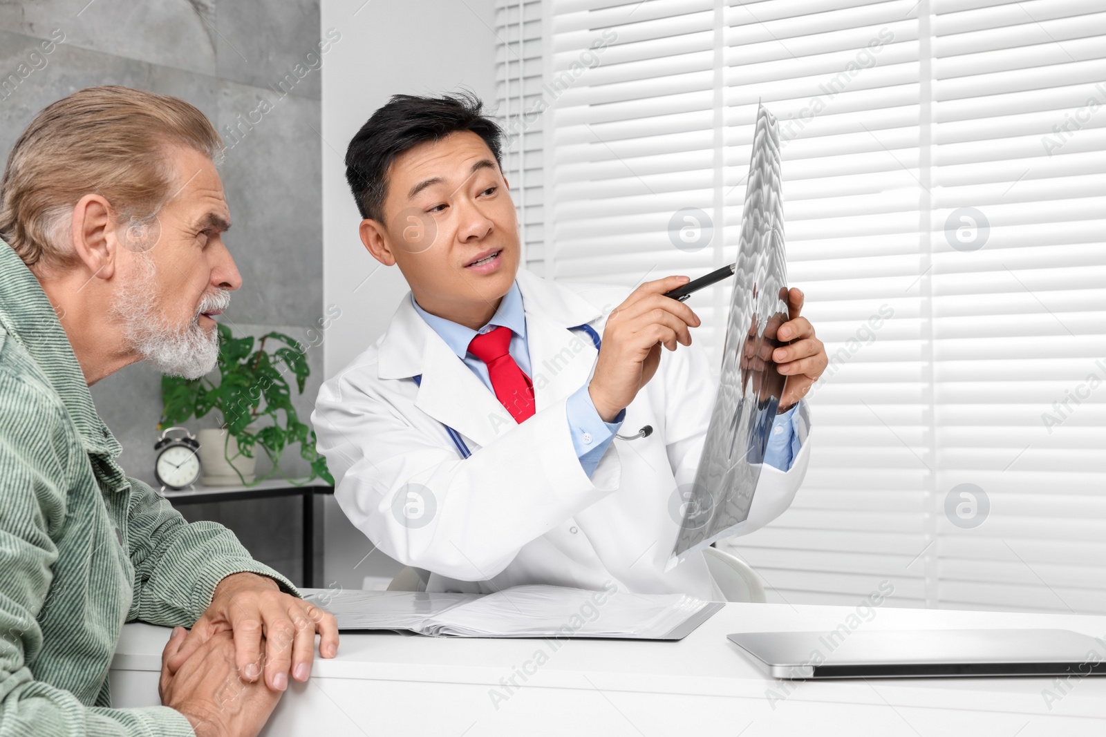 Photo of Doctor showing MRI images to senior patient in hospital