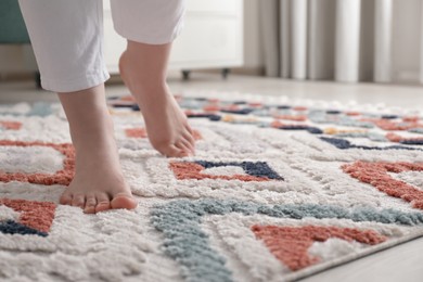 Photo of Woman standing on carpet with pattern at home, closeup. Space for text