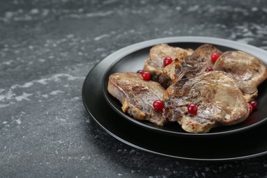 Photo of Tasty beef tongue pieces on dark textured table, closeup. Space for text