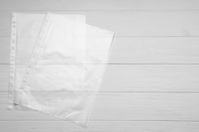 Photo of Punched pockets on white wooden table, flat lay. Space for text