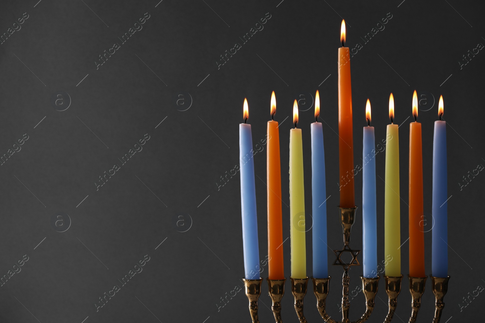 Photo of Hanukkah celebration. Menorah with burning candles on grey background, closeup. Space for text