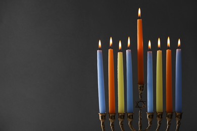 Photo of Hanukkah celebration. Menorah with burning candles on grey background, closeup. Space for text