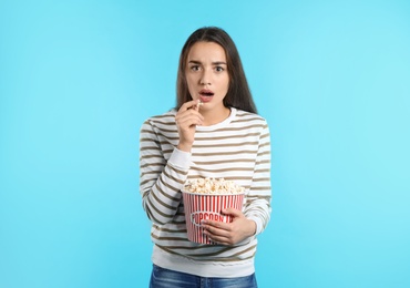 Photo of Emotional woman with popcorn during cinema show on color background