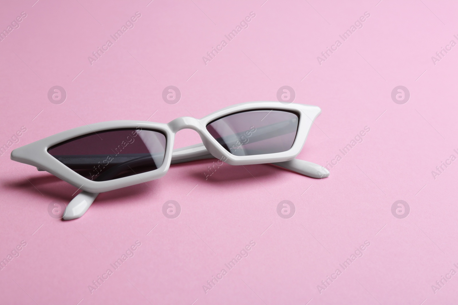 Photo of Stylish sunglasses on pink background. Fashionable accessory