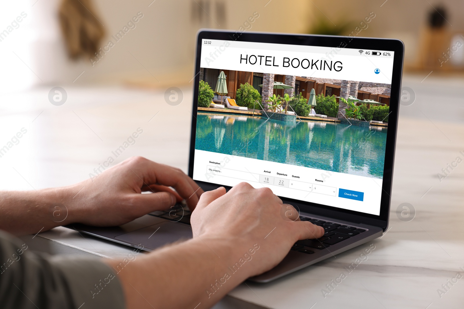 Image of Man using laptop to book hotel at white table, closeup