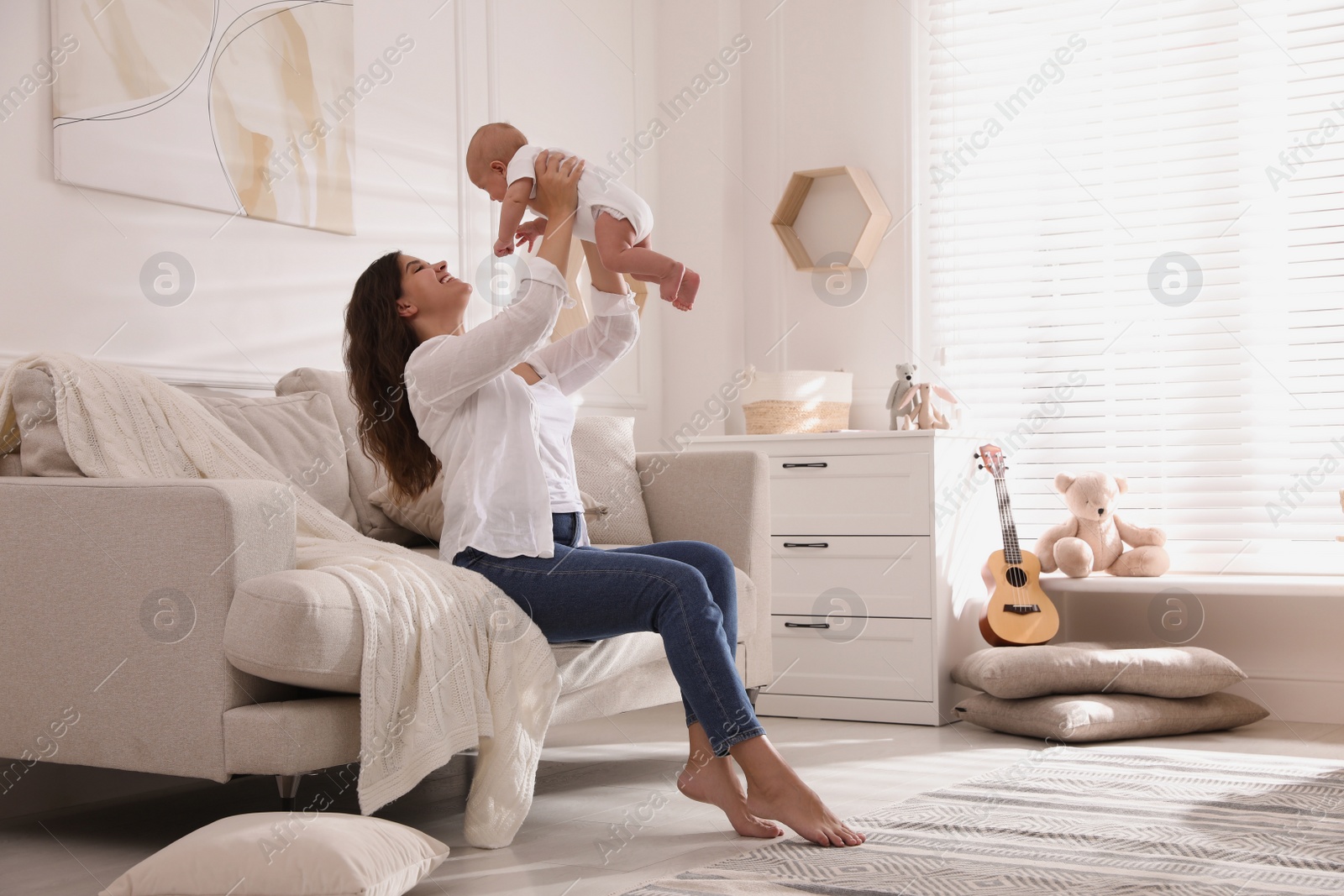 Photo of Happy young mother with her cute baby on sofa at home