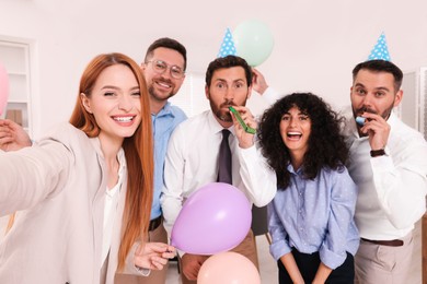 Photo of Coworkers taking selfie during office party indoors