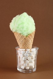 Photo of Sweet cotton candy in waffle cone on brown background, closeup