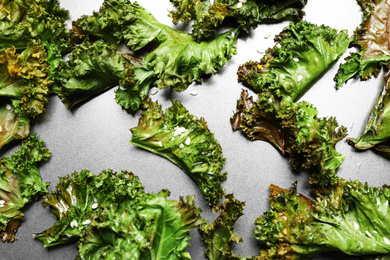 Tasty baked kale chips on grey table, flat lay