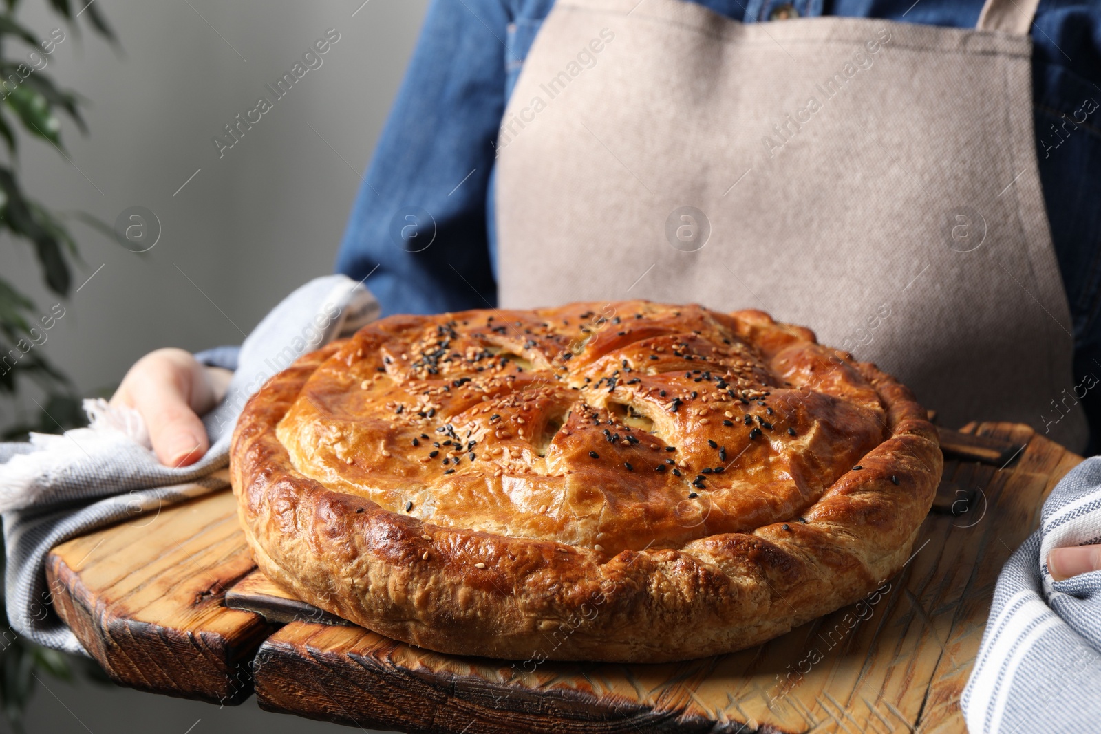 Photo of Woman holding tasty homemade pie indoors, closeup