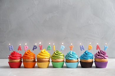 Photo of Delicious cupcakes with Happy Birthday candles on table