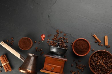 Flat lay composition with vintage manual coffee grinder and beans on black table, space for text