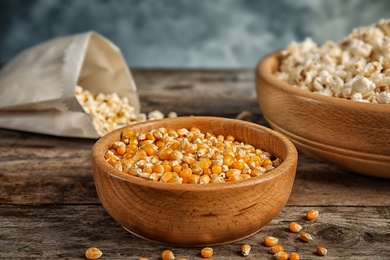 Photo of Bowl with kernels and popcorn on wooden table