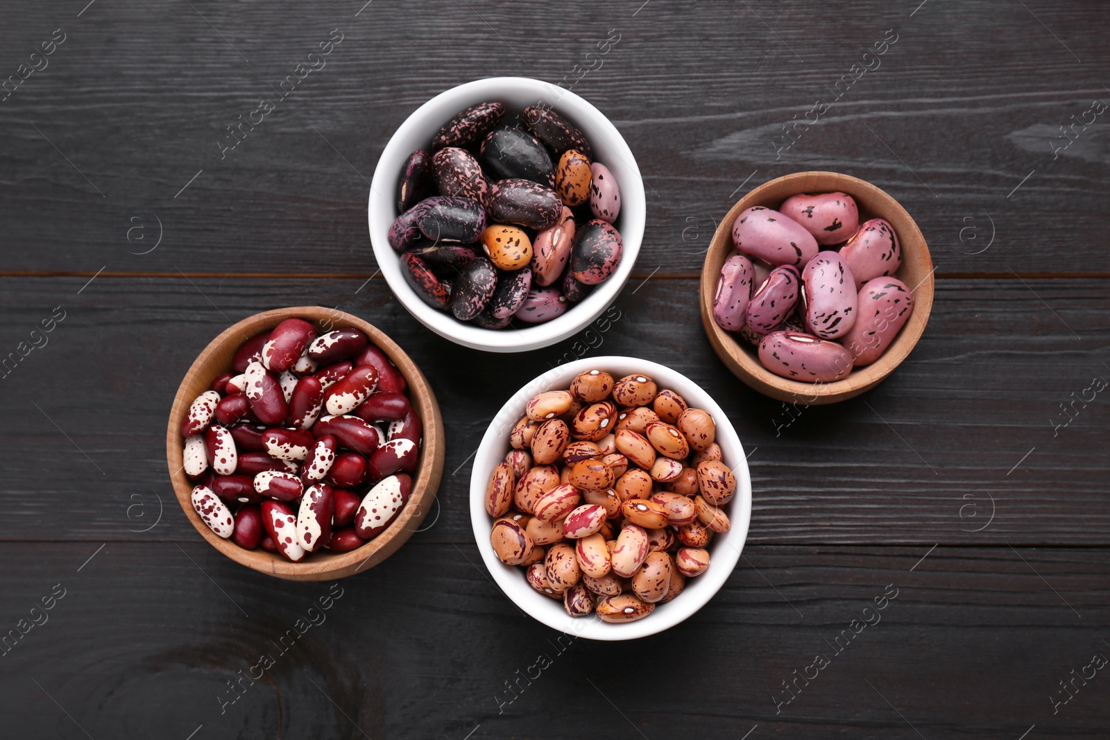 Photo of Different kinds of dry kidney beans on wooden table, flat lay