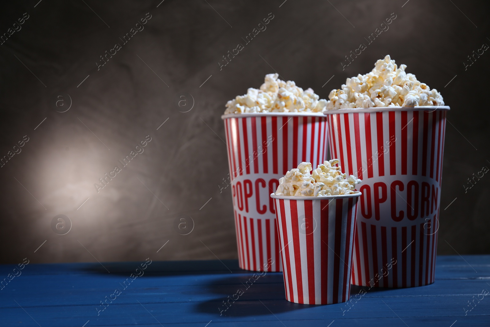 Photo of Delicious popcorn on blue wooden table. Space for text