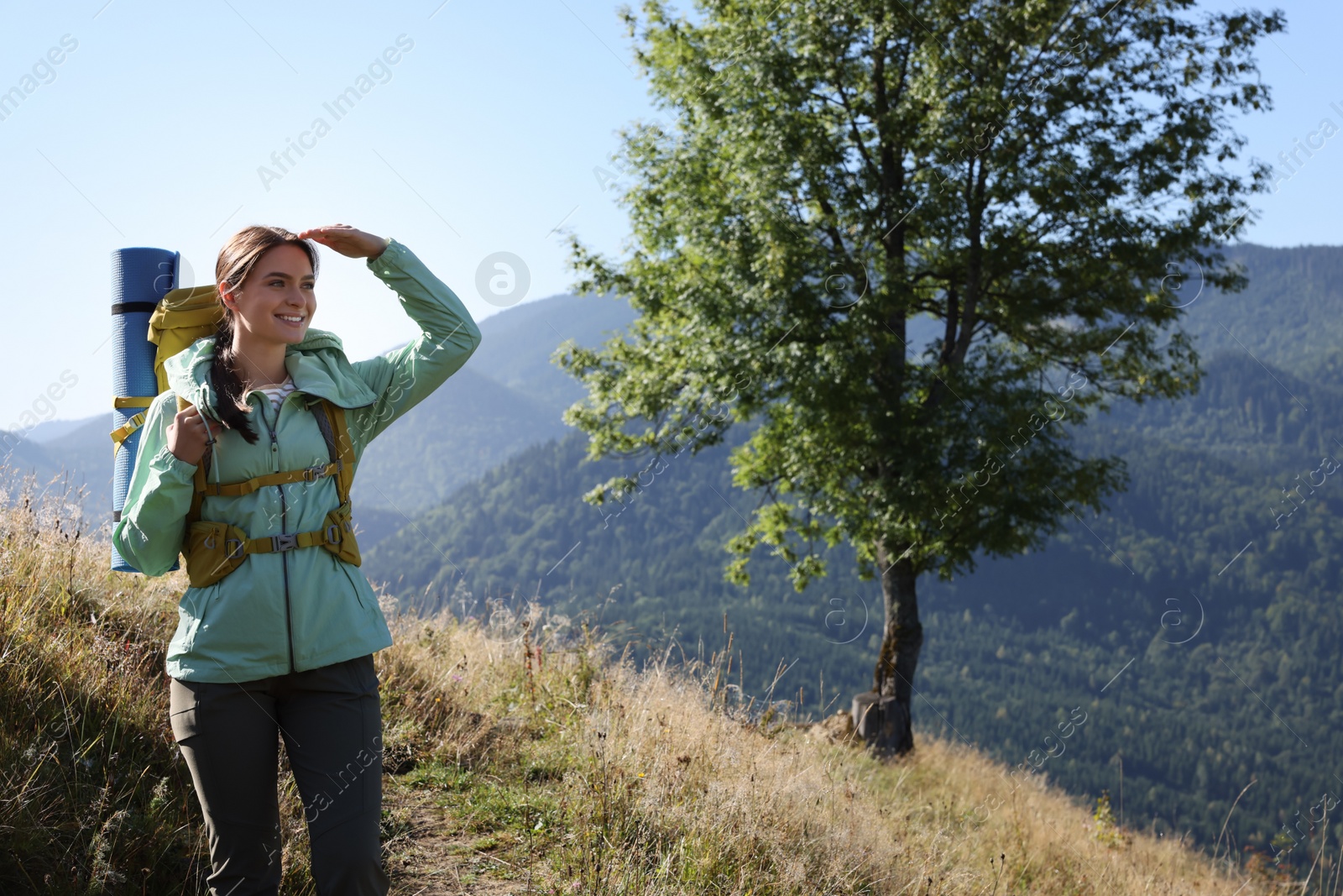 Photo of Tourist with backpack and sleeping pad in mountains on sunny day