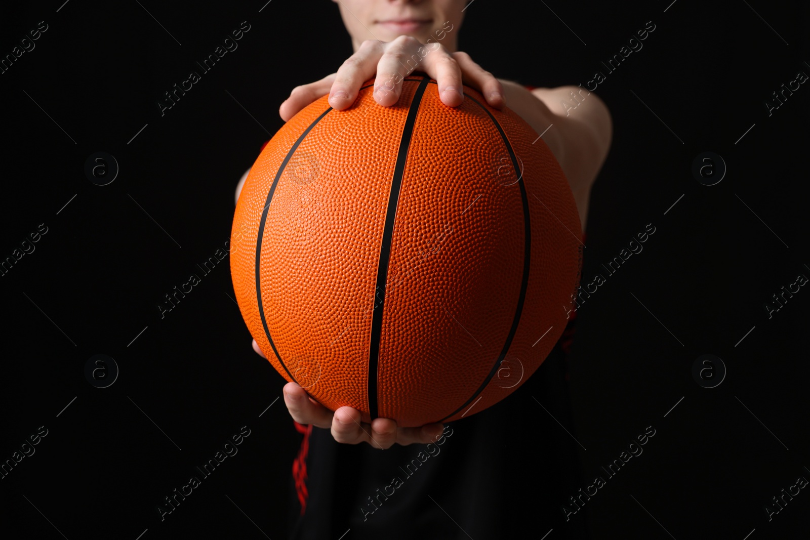 Photo of Boy with basketball ball on black background, closeup
