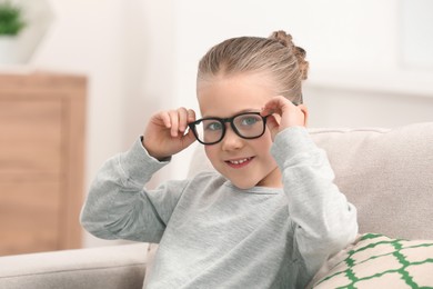 Portrait of smiling little girl wearing glasses indoors