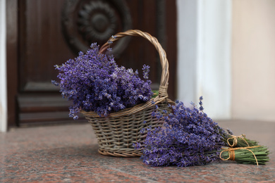 Photo of Beautiful lavender flowers and wicker basket near building outdoors