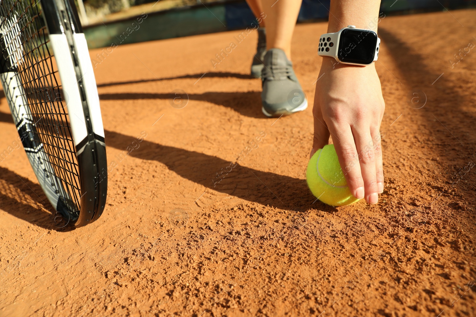 Photo of Woman wearing modern smart watch during training on tennis court, closeup