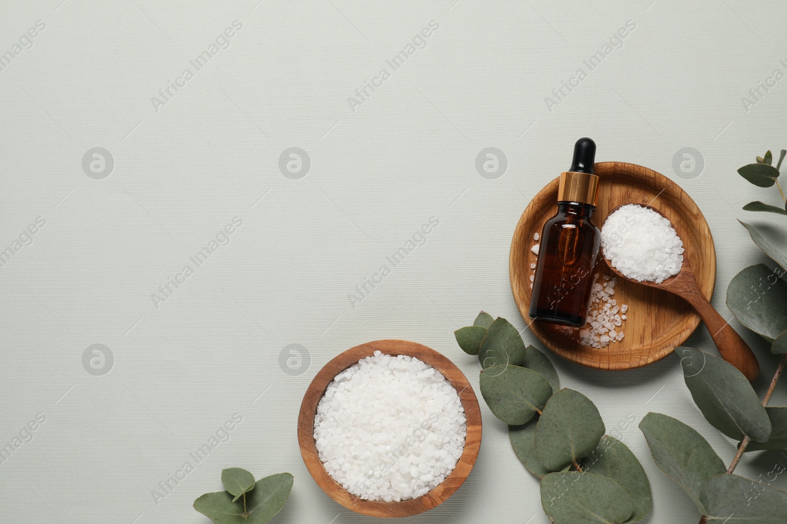 Photo of Aromatherapy products. Bottles of essential oil, sea salt and eucalyptus leaves on grey background, flat lay. Space for text
