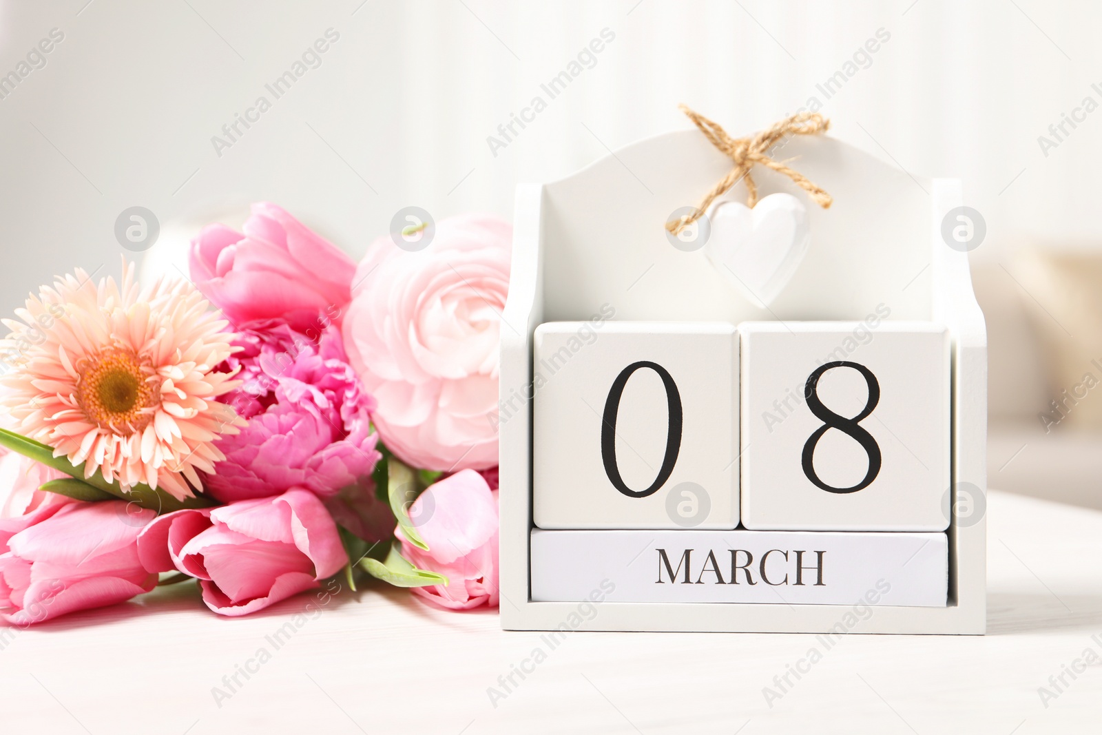 Photo of International Women's day - 8th of March. Block calendar and bouquet of beautiful flowers on white wooden table