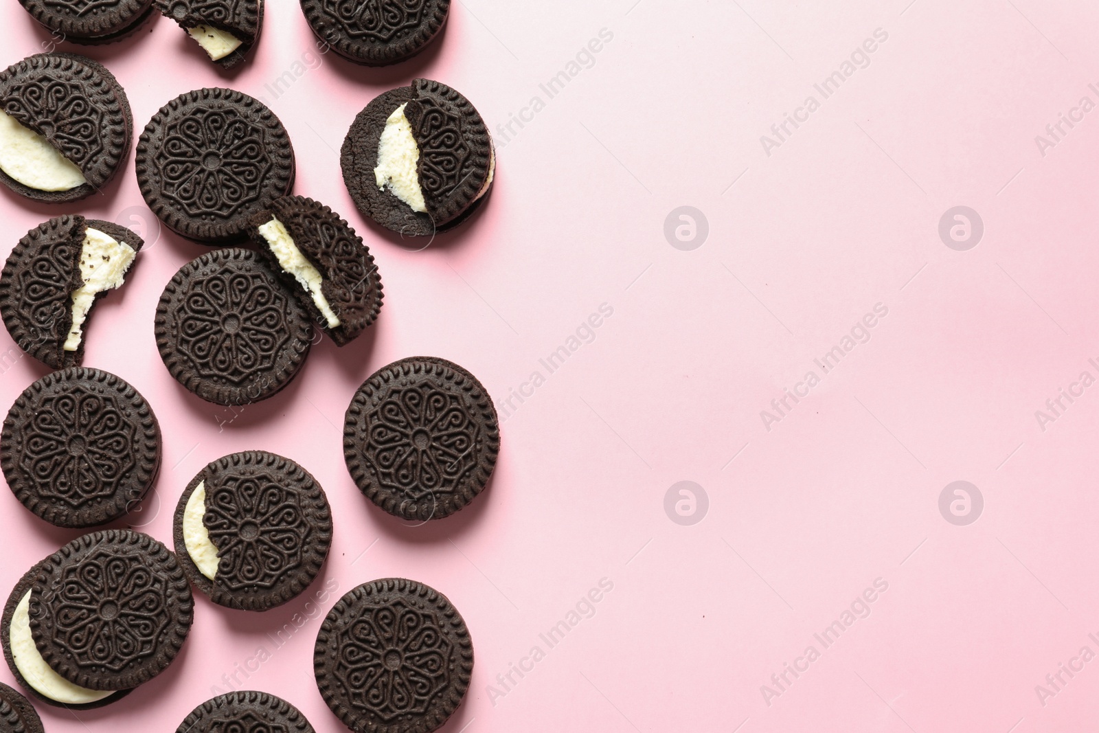 Photo of Tasty chocolate cookies with cream on color background, flat lay. Space for text