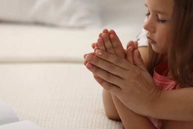 Photo of Mature woman with her little granddaughter praying together indoors, closeup. Space for text