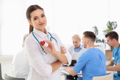 Female doctor holding small heart in clinic. Cardiology center