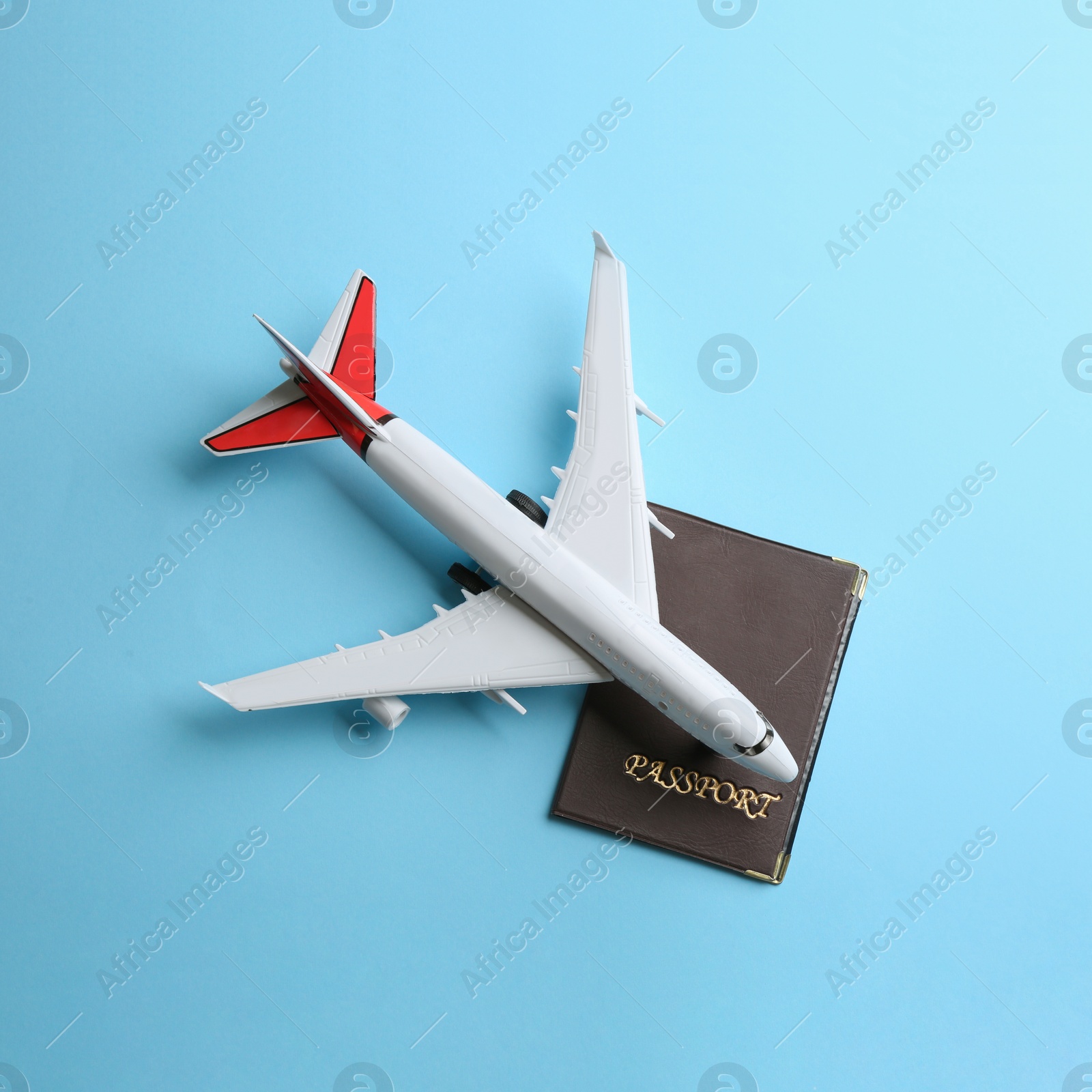 Photo of Toy airplane and passport on light blue background, flat lay