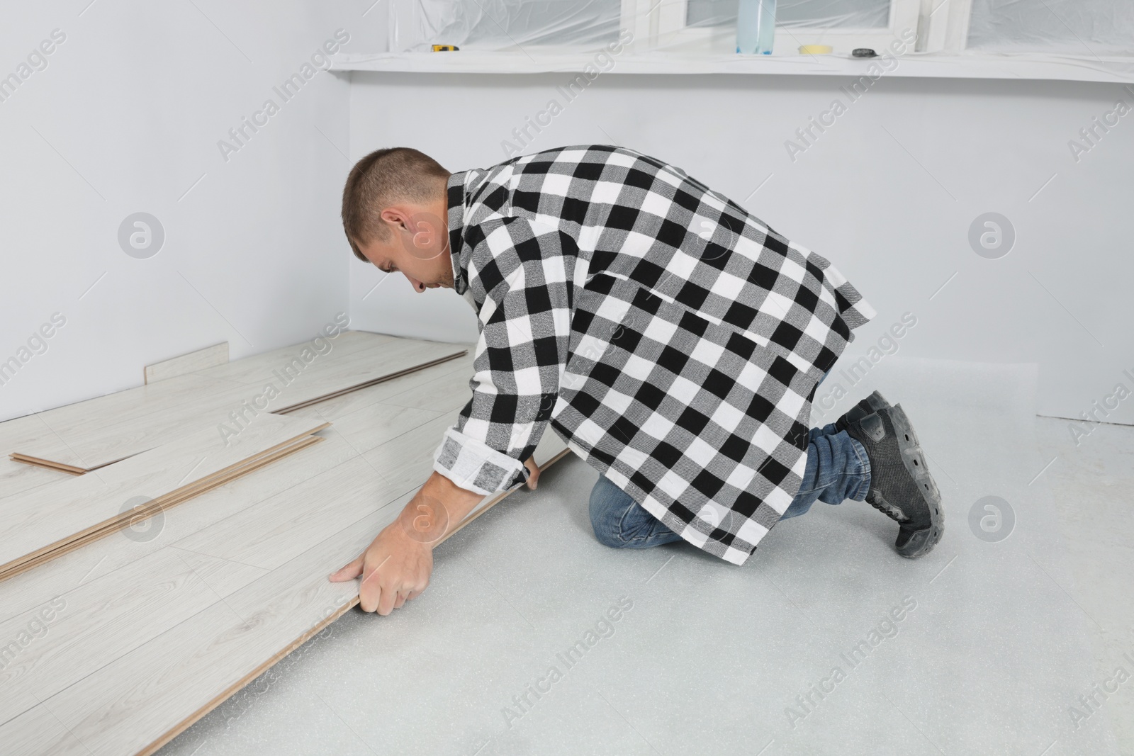 Photo of Professional worker installing new laminate flooring indoors