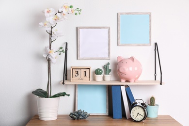 Photo of Color piggy bank on shelf over table in room. Cute interior element