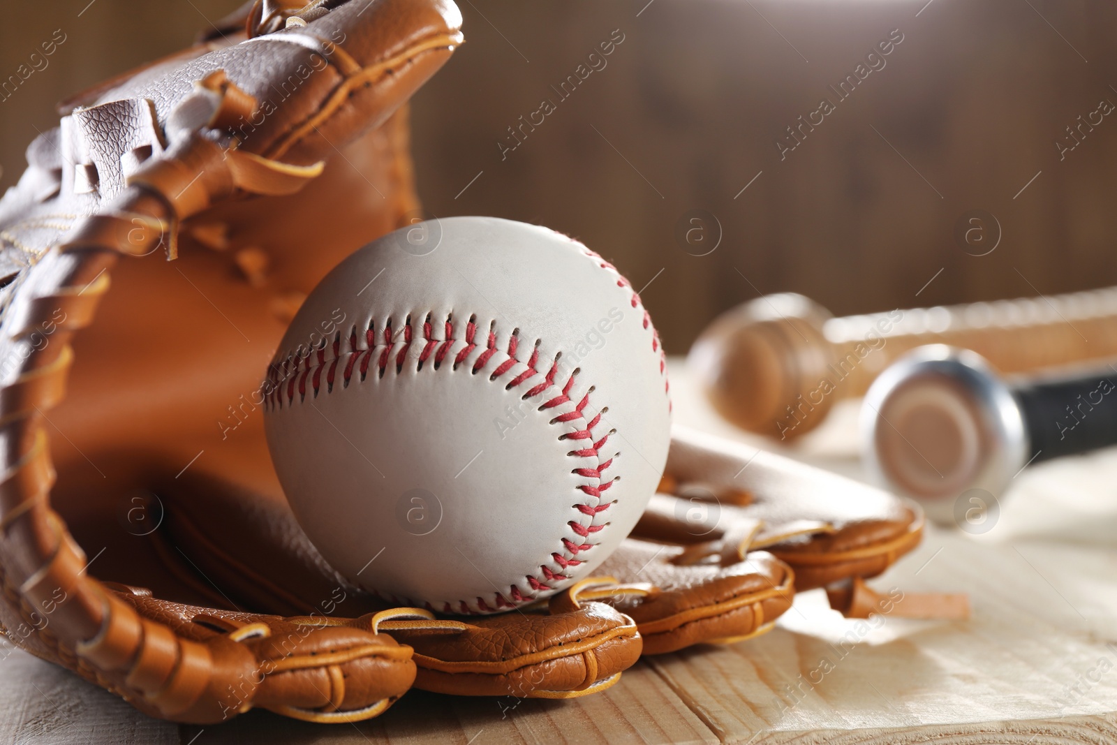 Photo of Baseball glove and ball on wooden table, closeup