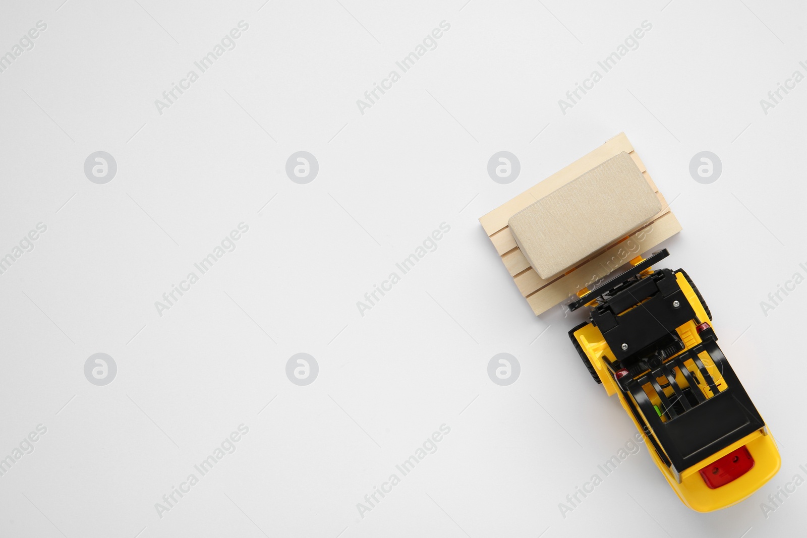 Photo of Toy forklift with wooden pallet and box on white background, top view