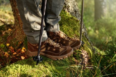 Photo of Man with trekking poles hiking in forest, closeup