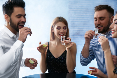 Photo of Young people with Mexican Tequila shots at table in bar