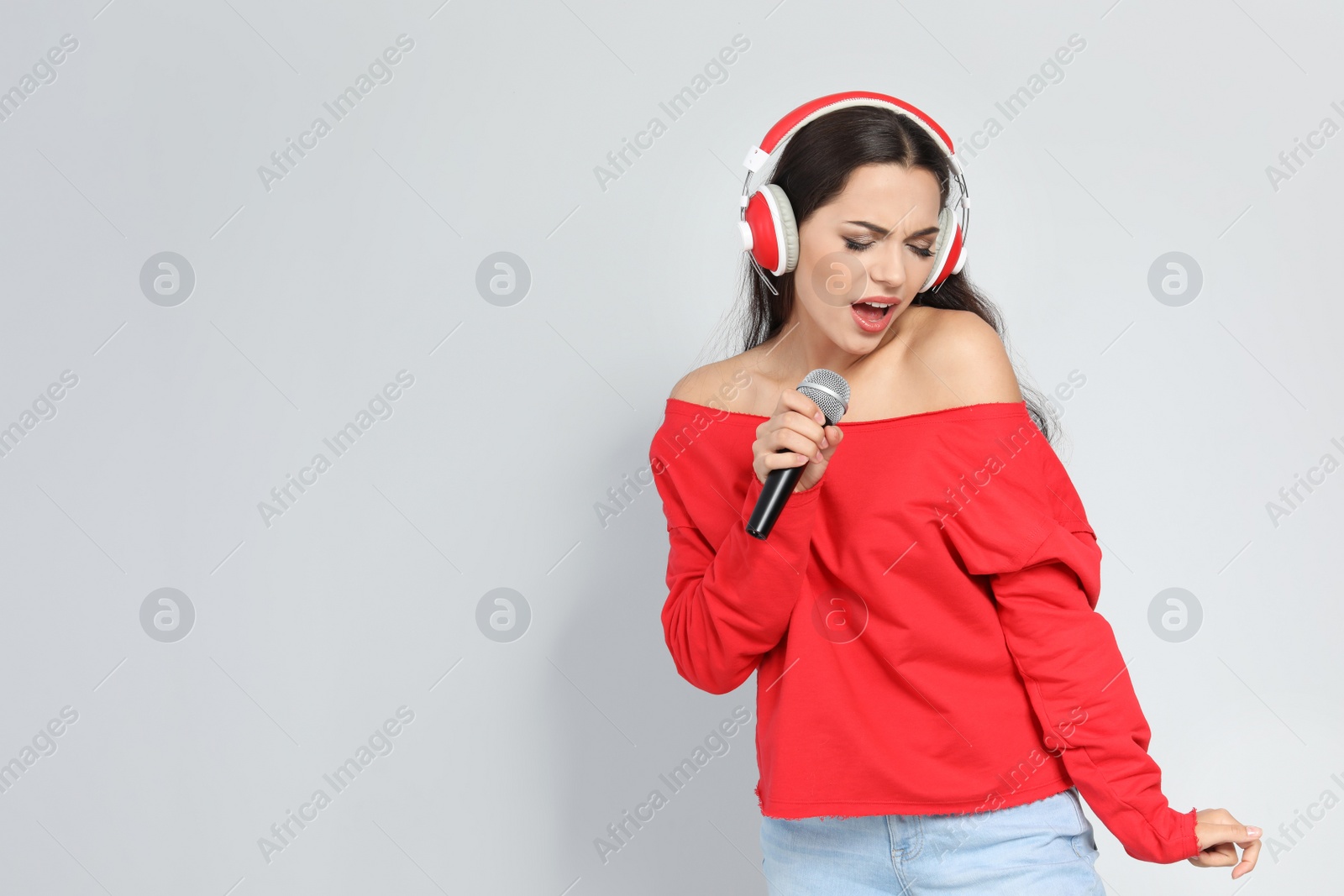 Photo of Young woman singing into microphone on color background. Christmas music