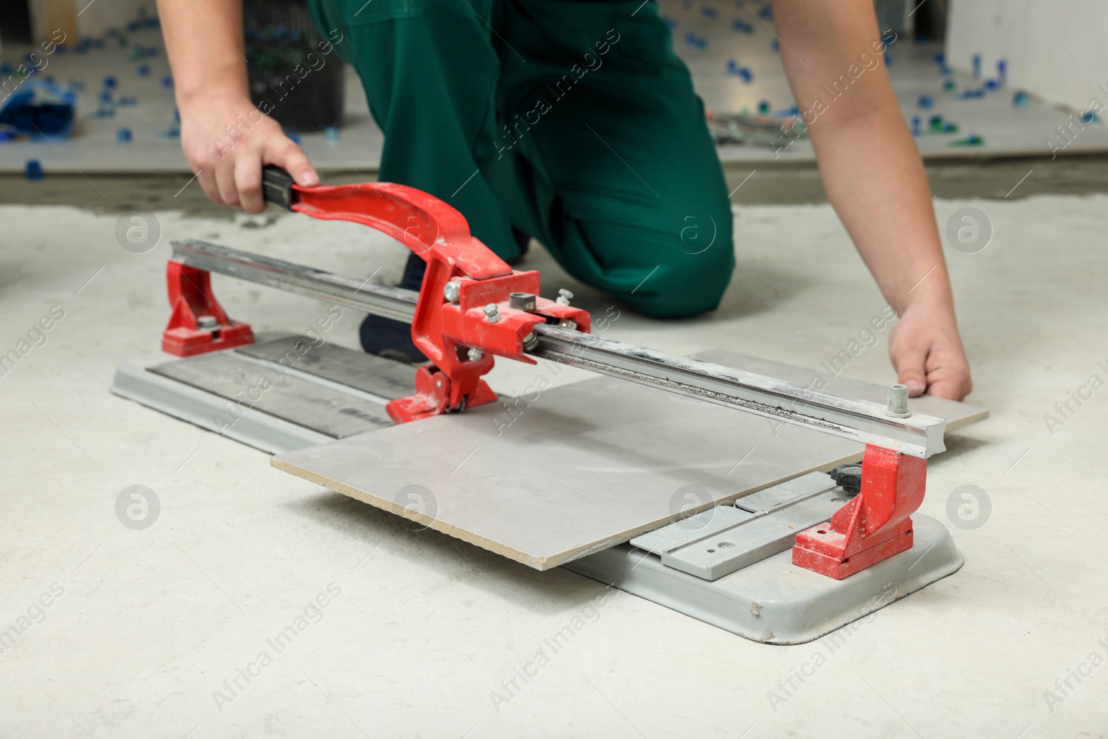 Photo of Worker using manual tile cutter on floor, closeup