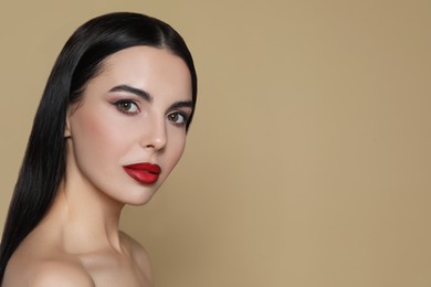 Photo of Portrait of young woman wearing beautiful red lipstick on beige background, space for text