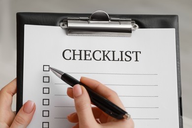 Photo of Woman filling Checklist with pen, closeup view